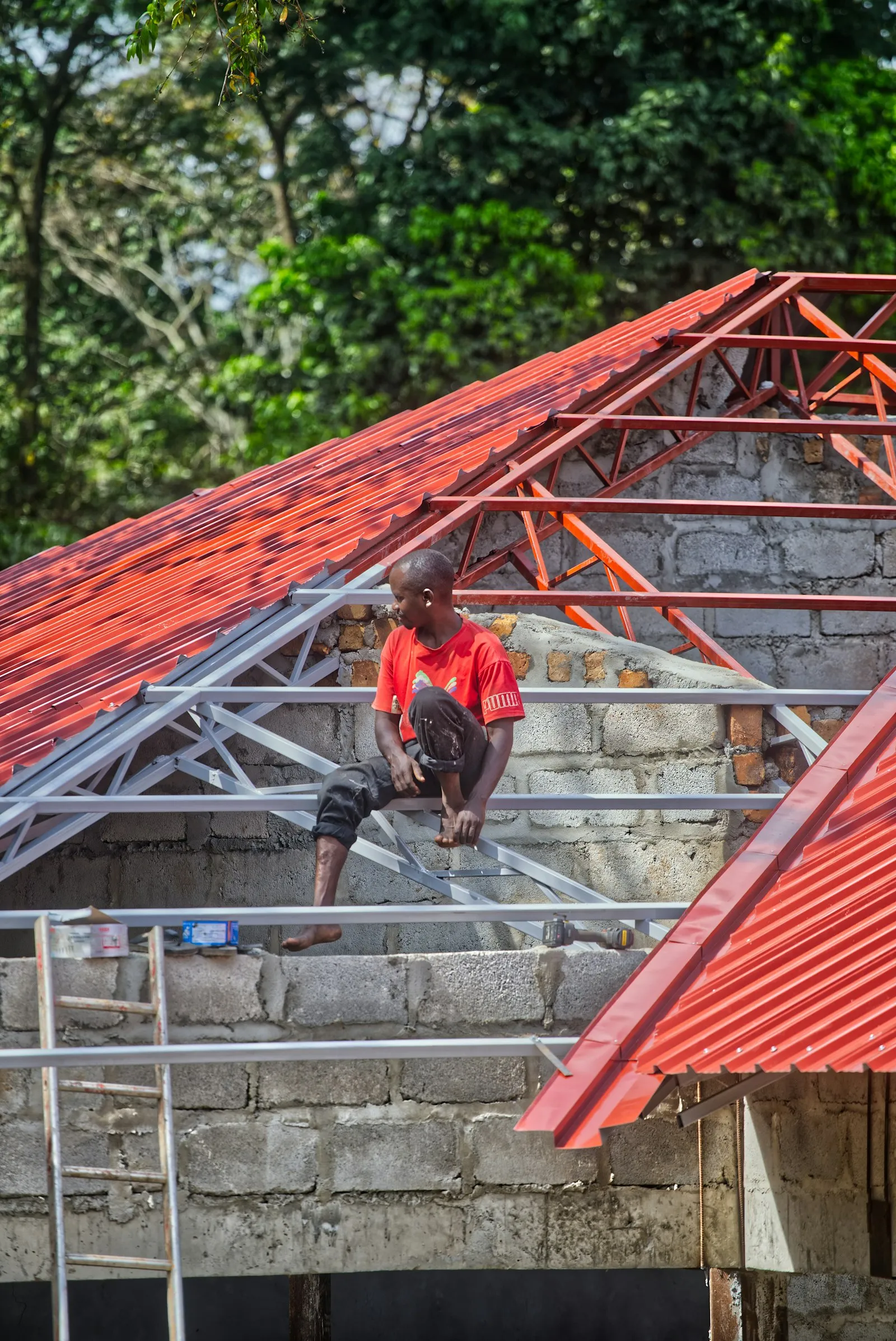 Pekerja memasang genteng metal merah baru pada rangka atap di Bogor Barat